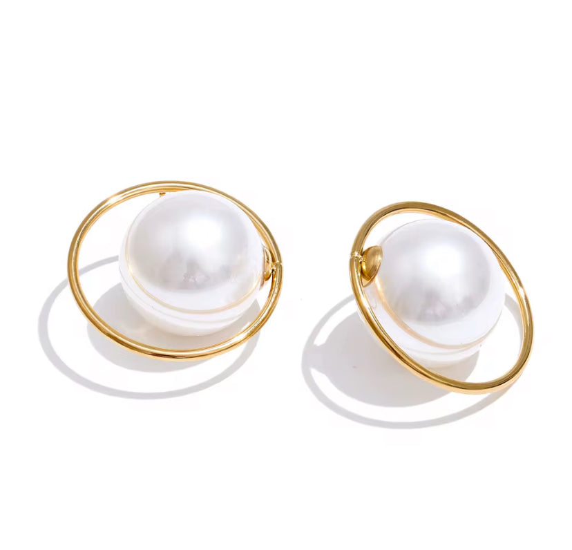 Oversized white pearl stud earrings encircled by a thin gold hoop ring, displayed on white background.