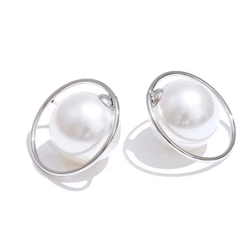 Oversized white pearl stud earrings encircled by a thin silver hoop ring, displayed on white background.
