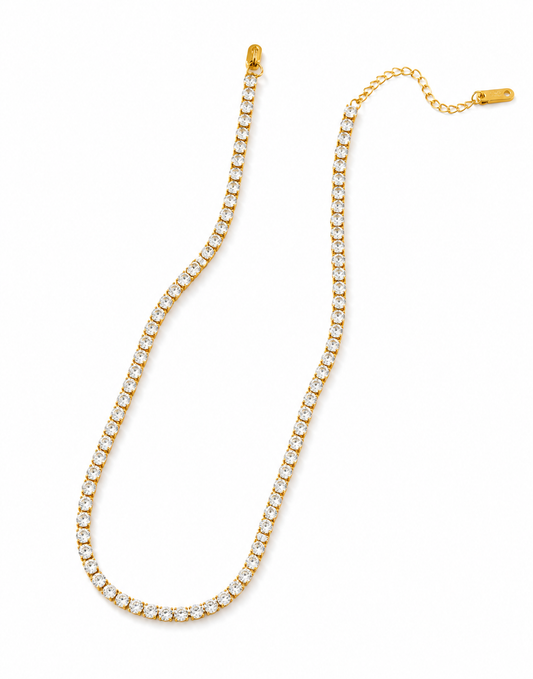 Gold crystal tennis necklace with continuous row of round cut stones in prong settings and adjustable extender chain, displayed on white background.
